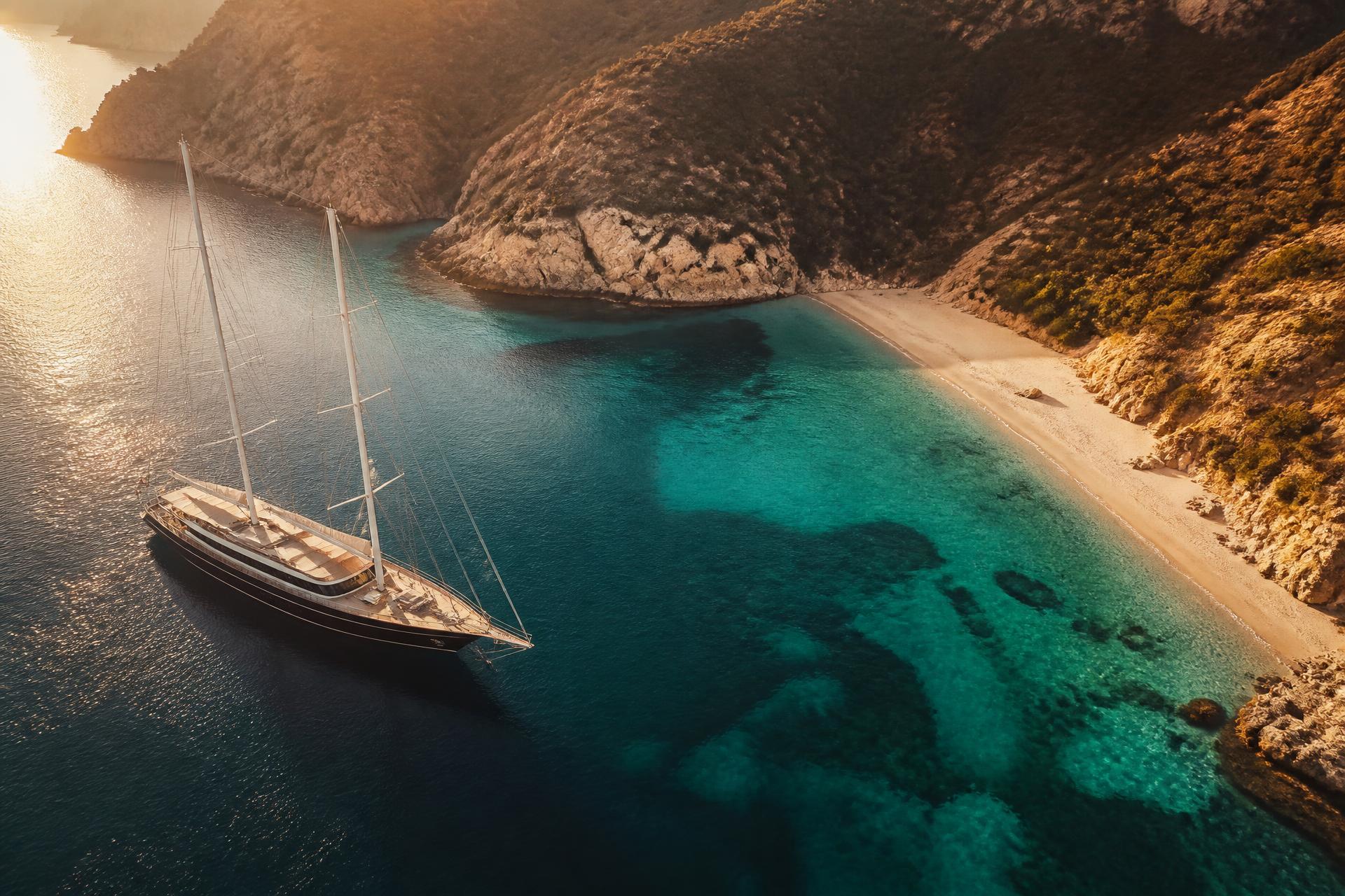 Luxury sailing yacht anchored in a turquoise bay at golden hour